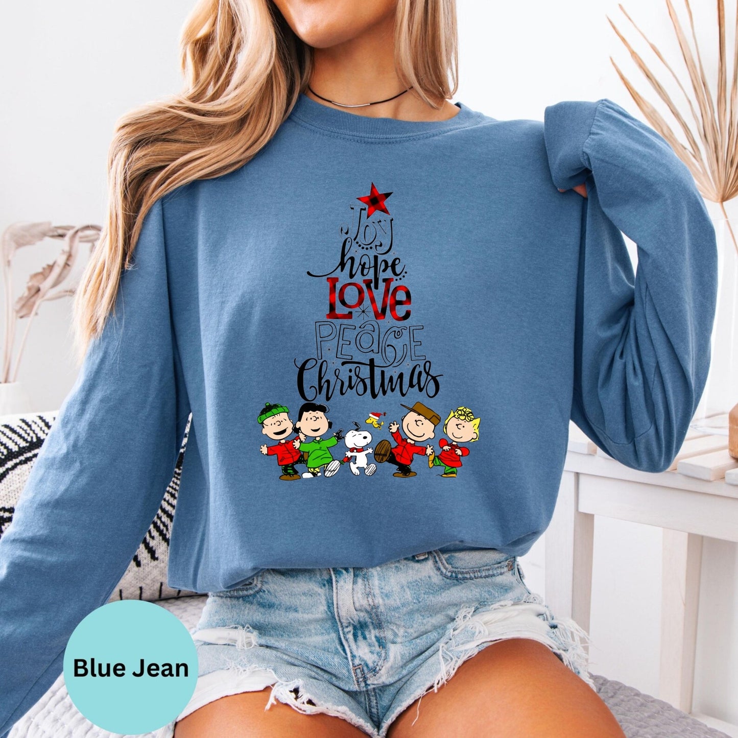 Person wearing a blue long-sleeve shirt with Christmas-themed design and denim shorts.