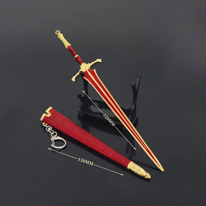 Mini medieval greatsword replica displayed on stand with red scabbard and keychain