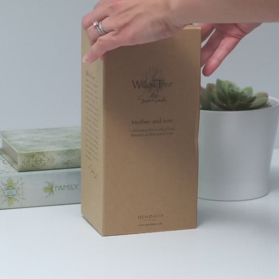 Hands opening a Willow Tree figurine box to reveal the hand-painted sculpture inside
