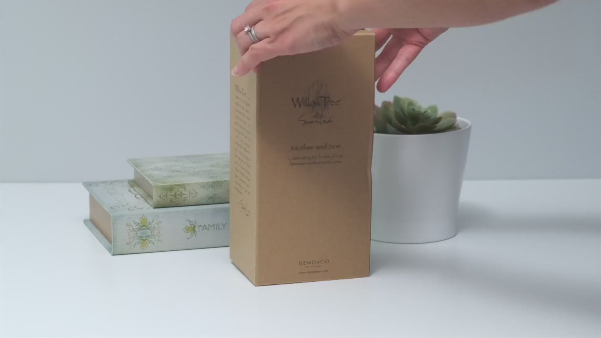 Hands opening a Willow Tree figurine box to reveal the hand-painted sculpture inside