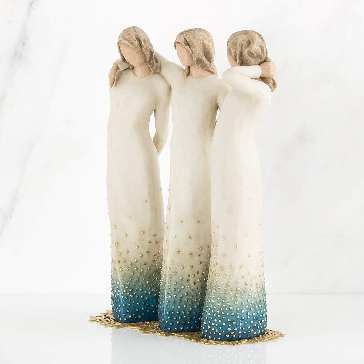 Three figures in white dresses with gradient blue and gold designs on a white background