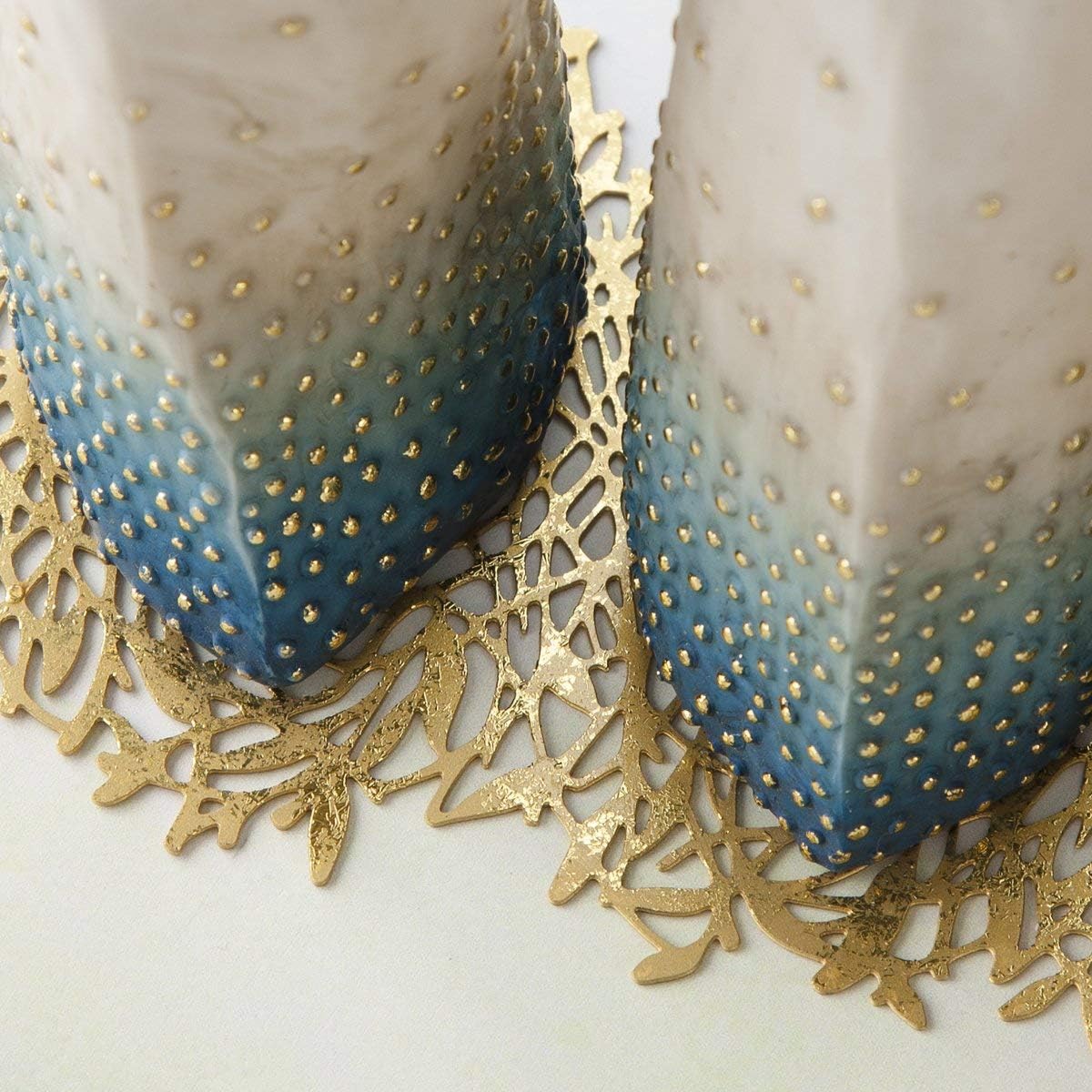 Two decorative candles with gold polka dots and a gold lace doily on a white background