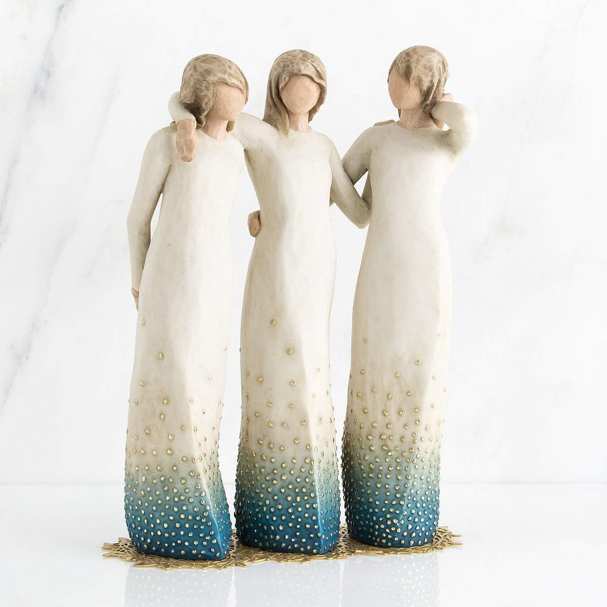 Three angel figurines with gradient dresses on a white background