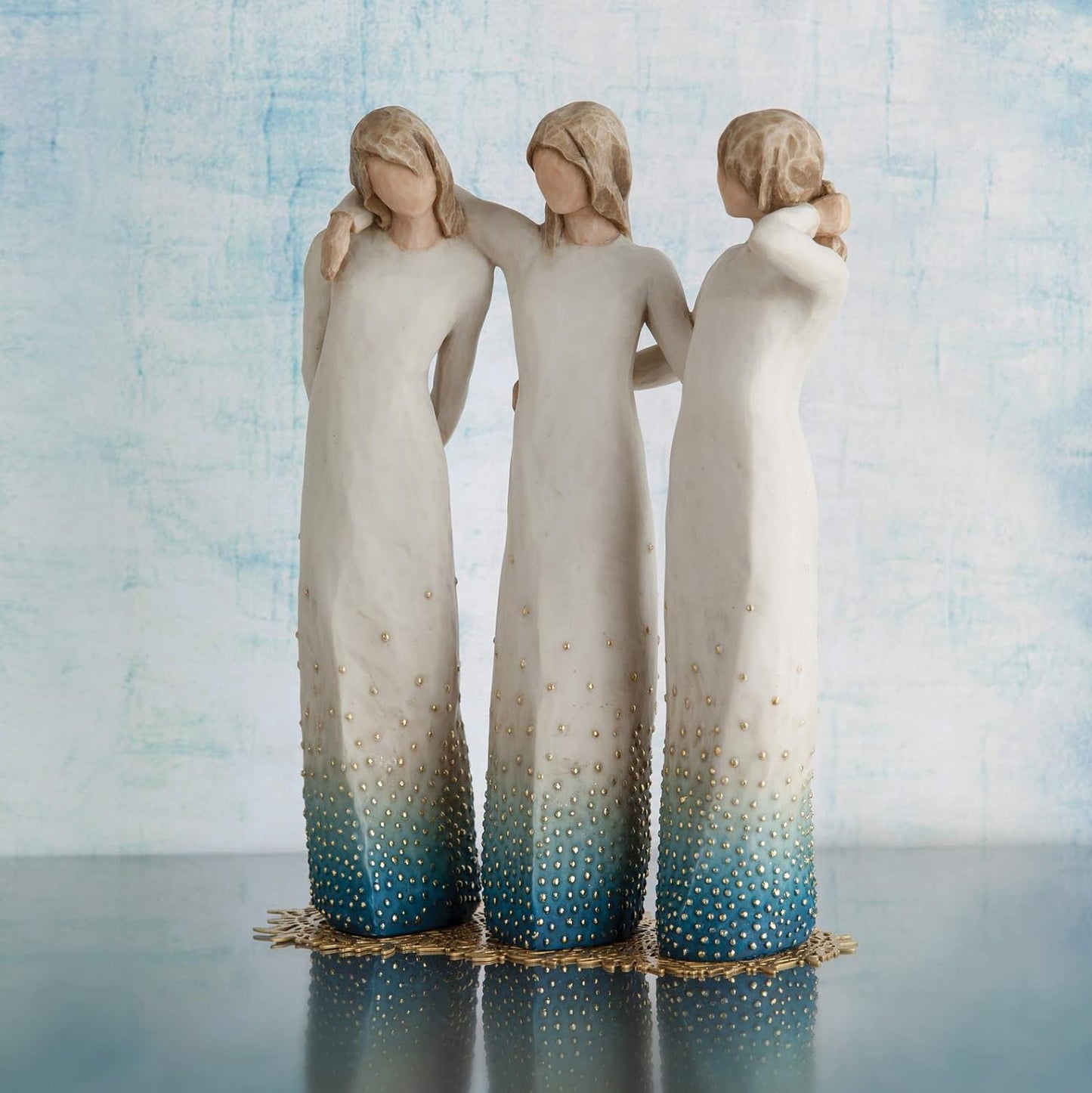 Three angel figurines with gradient blue and white dresses against a light blue background