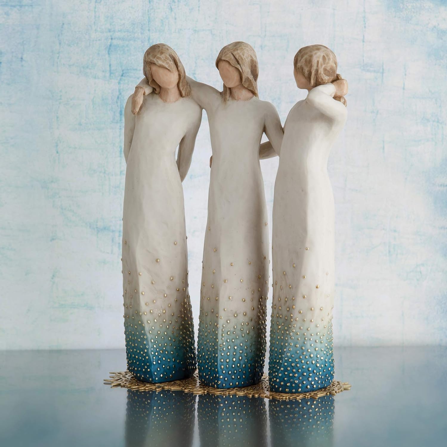 Three angel figurines with gradient blue and white dresses against a light blue background