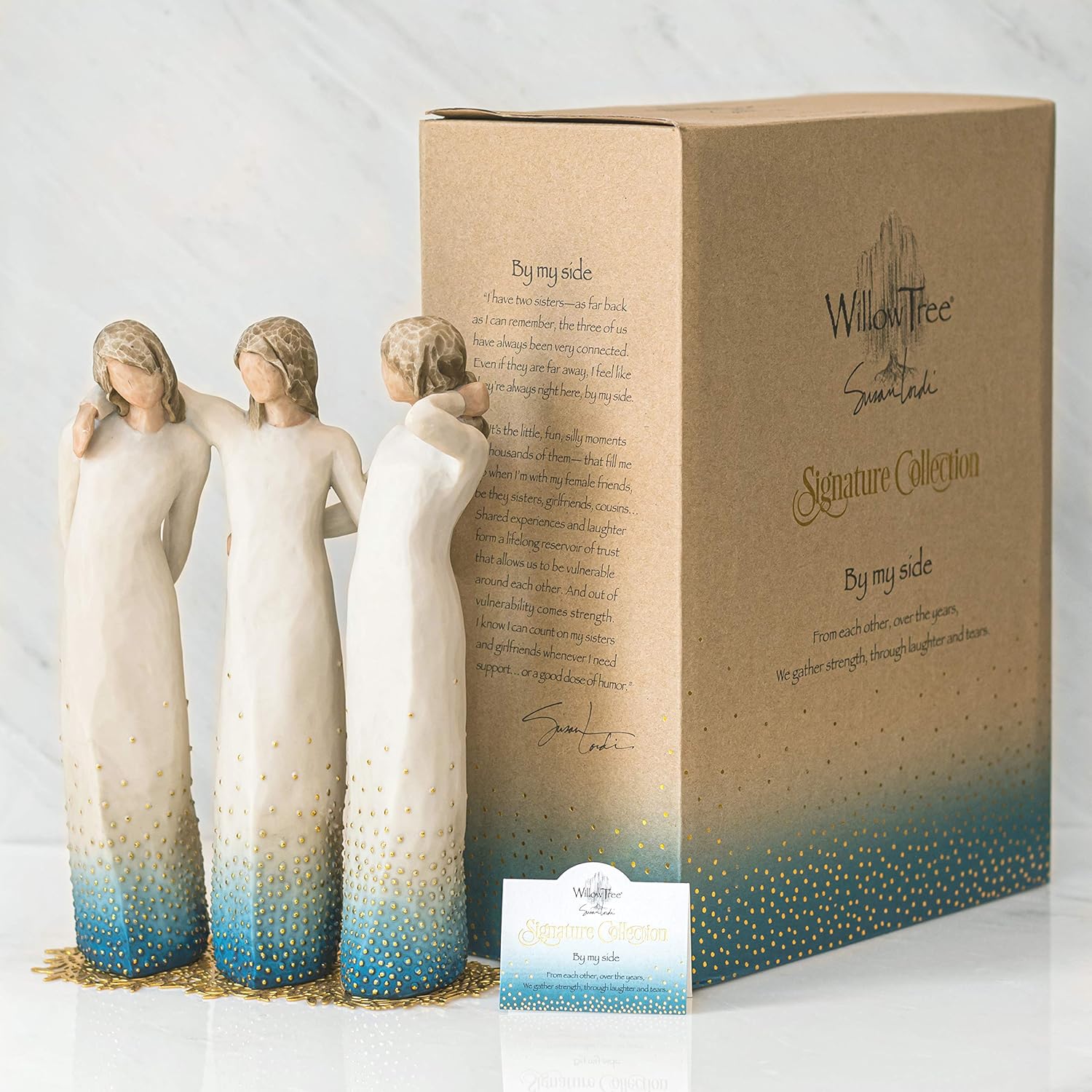 Three angel figurines with gradient blue and gold coloring in front of a Willow Tree packaging box.