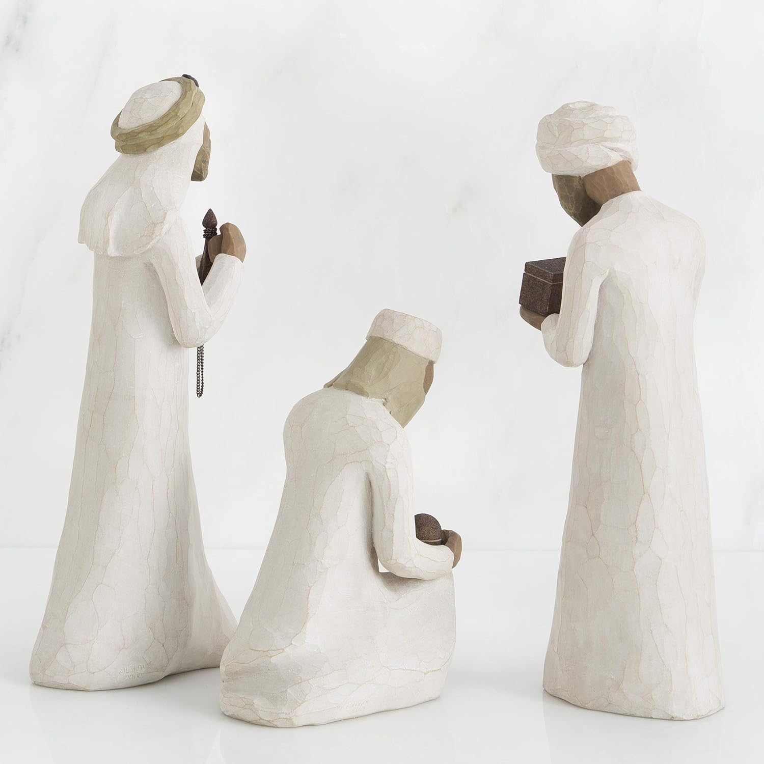 Three white figurines with headscarves on a white background