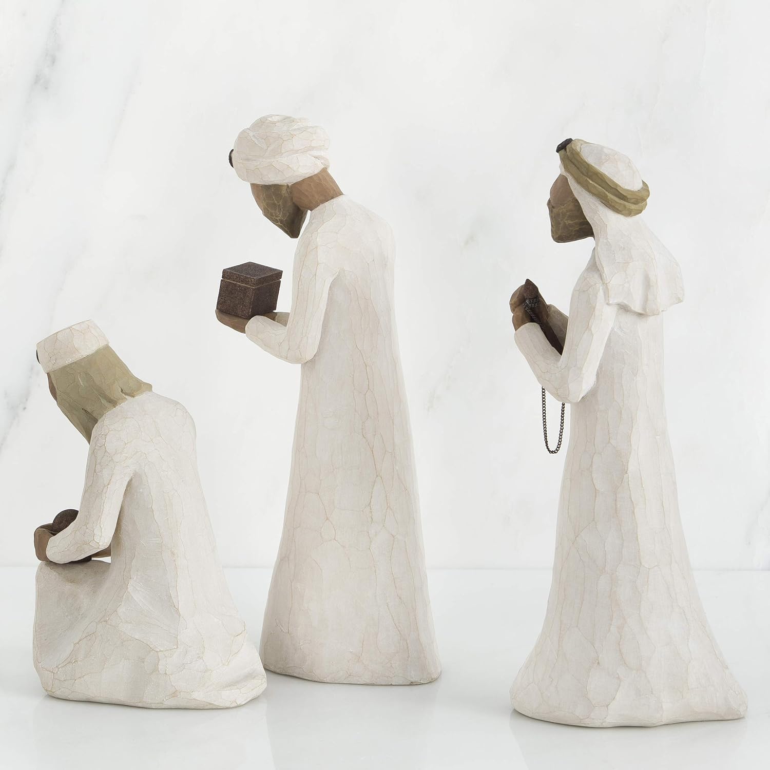 Three stone statues of people in different poses on a white background