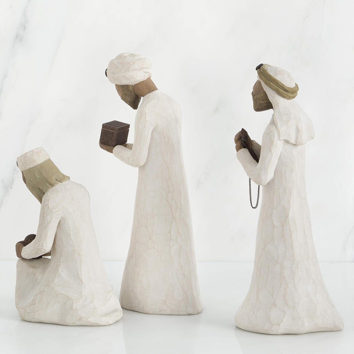 Three stone statues of people in different poses on a white background