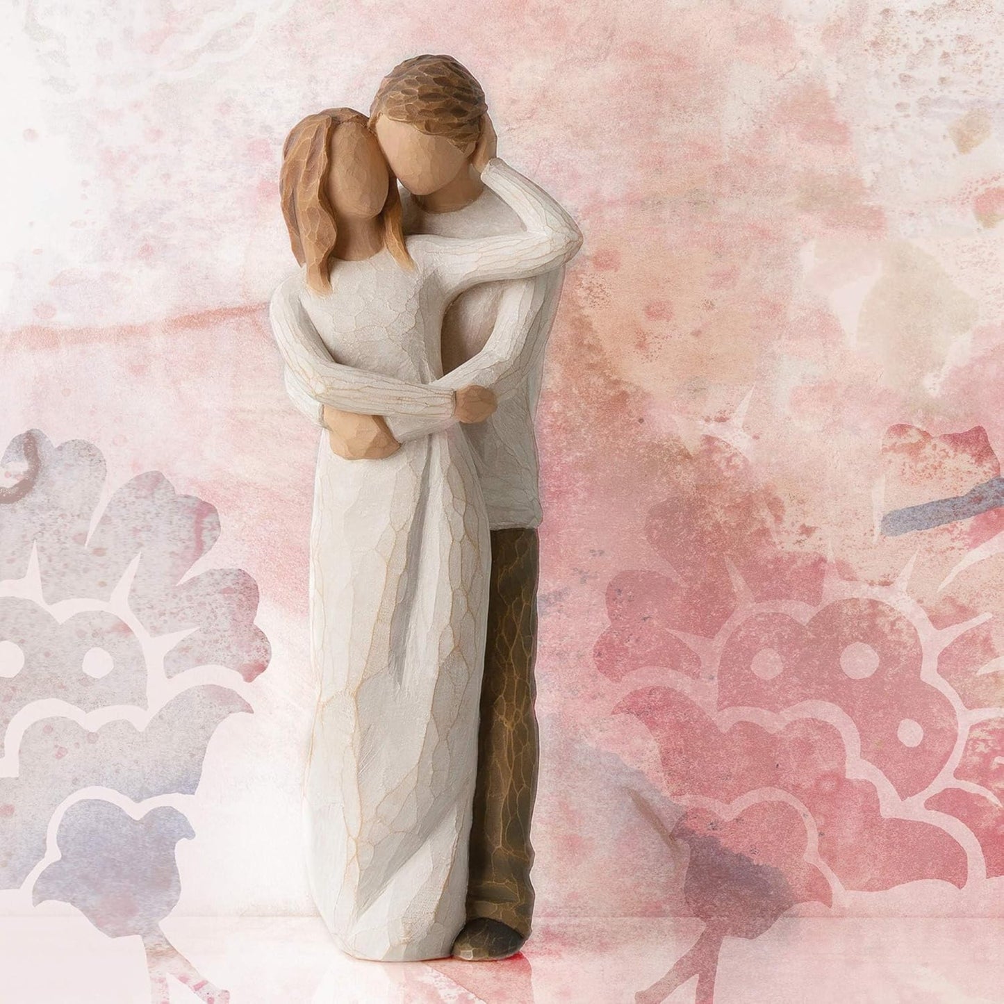 Statue of a couple embracing on a pink floral background